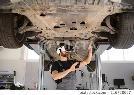 Mechanic using virtual reality to inspect car on lift Mechanic using virtual reality to inspect car on lift 116728697