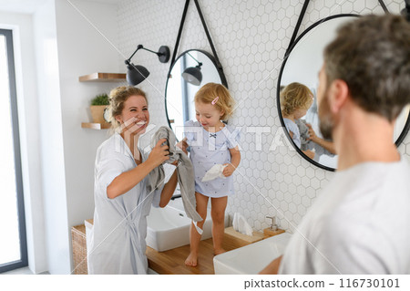 Parents and daughter having morning bathroom routine, brushing teeth and washing face, enjoying together time. 116730101