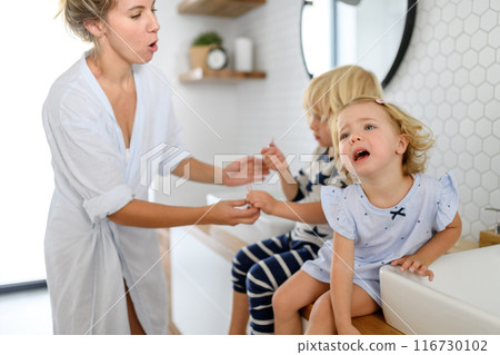 Parents and kids having morning bathroom routine, brushing teeth and washing face, enjoying together time. 116730102