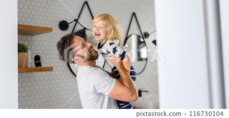 Father holding son in arms, standing in bathroom. Morning routine for young boy before going to preschool. 116730104