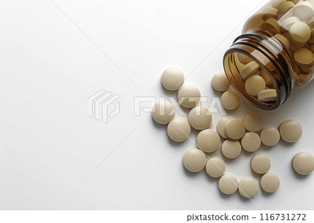 A bird's-eye view of flesh-colored medicinal tablets spilling out of a translucent brown vial 116731272