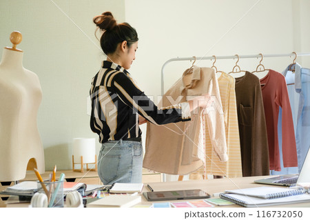 Young clothing designer taking measures of her clothes. 116732050