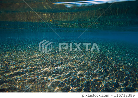Underwater crystal ocean with stone bottom and reflection on surface. Sea textures 116732399