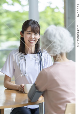 Smiling nurse taking a senior woman's blood pressure 116733534
