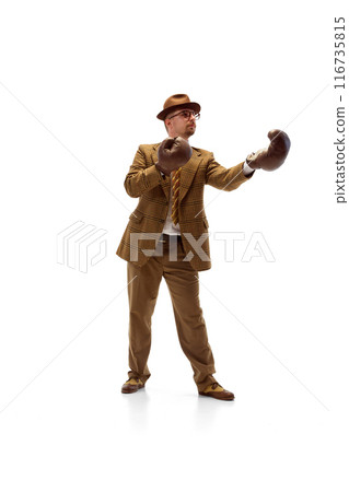 Man in formal outfit stands in boxing stance wearing boxing gloves, focused and ready to spar against white studio background. Man in formal outfit stands in boxing stance wearing boxing gloves, focused and ready to spar against white studio background. 116735815