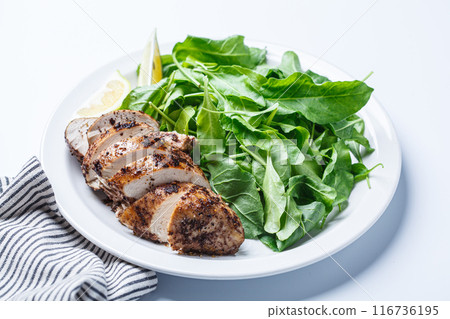 Green salad with grilled chicken breast on white plate, white background. Green salad with grilled chicken breast on white plate, white background. 116736195