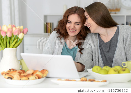 Two happy friends watching movie on laptop eating  116736322