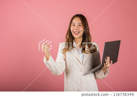 Portrait of happy Asian beautiful business woman teen confident smiling face holding using laptop computer and excited celebrating success, studio shot isolated on pink background, with copy space 116736349