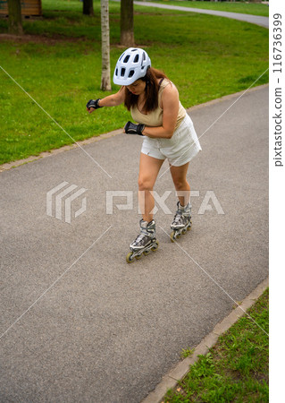 Roller skater woman in park rollerblading on inline skates. Outdoor activities. Summer roller skating. 116736399