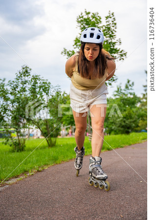 Roller skater woman in park rollerblading on inline skates. Outdoor activities. Summer roller skating. 116736404