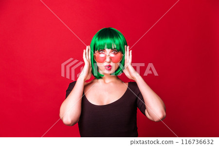 Playful Woman with Green Hair and Pink Sunglasses Posing in Black Top Playful Woman with Green Hair and Pink Sunglasses Posing in Black Top 116736632