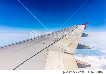 View from the airplane window at a beautiful cloudy sky and the airplane wing View from the airplane window at a beautiful cloudy sky and the airplane wing 116738082