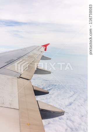 View from the airplane window at a beautiful cloudy sky and the airplane wing View from the airplane window at a beautiful cloudy sky and the airplane wing 116738083