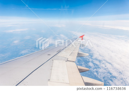 View from the airplane window at a beautiful cloudy sky and the airplane wing 116738636