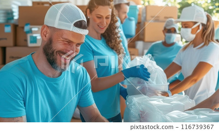 Group of young people, volunteers wearing blue shirts and caps work together, packing supplies. Teamwork. 116739367