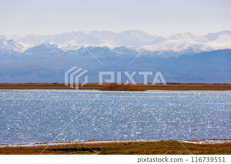 Blue calm water in Issyk-Kul lake with mountains on background at autumn afternoon 116739551