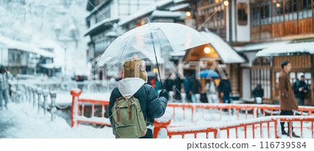 Woman tourist Visiting Ginzan Onsen in Yamagata, happy Traveler sightseeing Japanese Onsen village with Snow in winter season. landmark and popular for attraction in Japan. Travel and Vacation concept 116739584