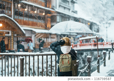 Woman tourist Visiting Ginzan Onsen in Yamagata, happy Traveler sightseeing Japanese Onsen village with Snow in winter season. landmark and popular for attraction in Japan. Travel and Vacation concept 116739587