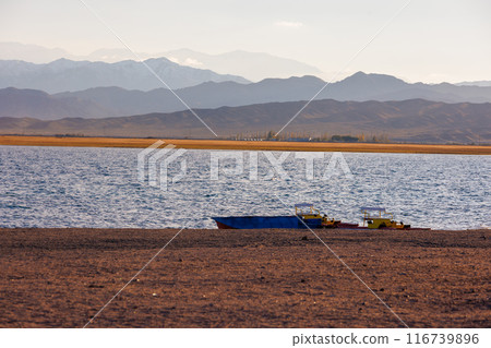 old pedal catamarans and boat on beach of mountain lake at sunny autumnal afternoon 116739896