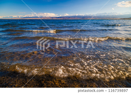 Ultra-wide angle view of small waves on mountain lake at sunny day. Low angle view. 116739897