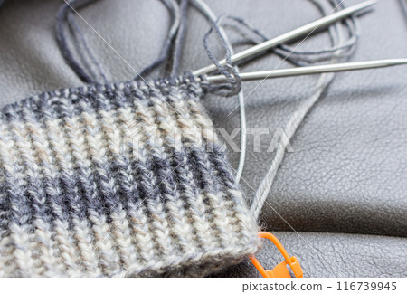 Knitting needles and crochet with orange marker. Knitting hobby. Striped pattern of wool yarn and knitting needles. Retro still life. Needlework concept. Homemade creativity. Vintage lifestyle. Knitting needles and crochet with orange marker. Knitting hobby. Striped pattern of wool yarn and knitting needles. Retro still life. Needlework concept. Homemade creativity. Vintage lifestyle. 116739945