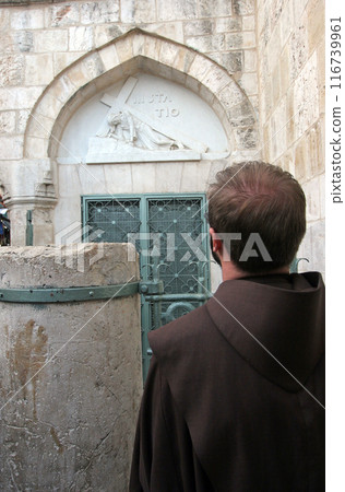 A Franciscan monk prays at the 3rd Stations of the Cross in the Via Dolorosa in Jerusalem, Israel 116739961