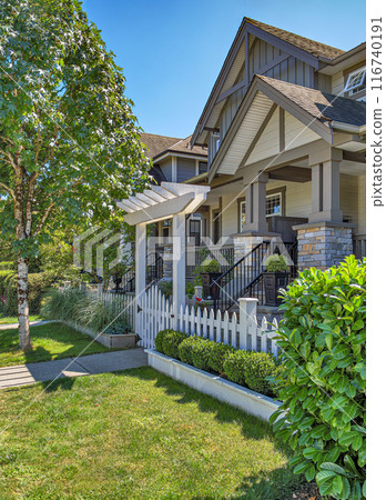 The porch of a nice residential house entrance with wooden gate and white birch in front 116740191