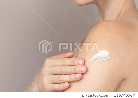 Naked caucasian woman spreads cream on her shoulders, takes care of herself, swatch of a cream. copy space nude background close up cropped photo Naked caucasian woman spreads cream on her shoulders, takes care of herself, swatch of a cream. copy space nude background close up cropped photo 116740567