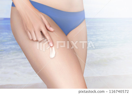 A woman looks after the skin on her leg. Friction Cream in the hip. Sun cream that protects with SPF. A beautiful example of white cream on the skin against the sea, nature close up 116740572