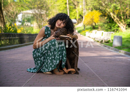 Pretty woman in long dress with her dog in the park Pretty woman in long dress with her dog in the park 116741094