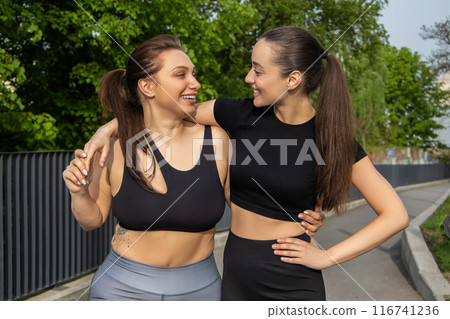 Plus-size woman in sports clothes standing with her female trainer outdoor Plus-size woman in sports clothes standing with her female trainer outdoor 116741236