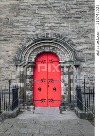 Facade of arched red wooden doorway on stone wall of Mansfield Traquair Centre in Edinburgh. 116742522