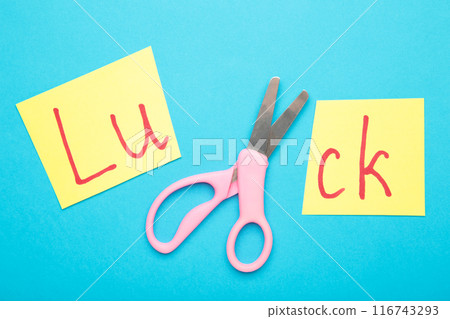 Cut paper with word LUCK and scissors on blue background, closeup. Cut paper with word LUCK and scissors on blue background, closeup. 116743293