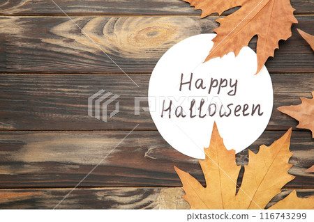 Colorful autumn leaves with inscription Happy halloween on brown background. 116743299