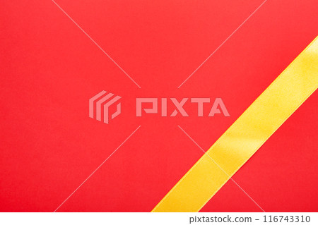 Shiny gold ribbon on red background with copy space. 116743310