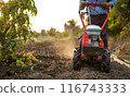 Farmer Using Rotary Tiller on a Plowed Field at Dawn 116743333