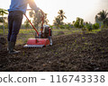 Farmer Using Rotary Tiller on a Plowed Field at Dawn 116743338