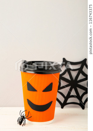 Paper cup with Halloween face in the blue background with spider. Vertical foto 116743375
