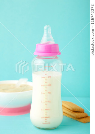 Milk and bowl with porridge for baby on blue background 116743378