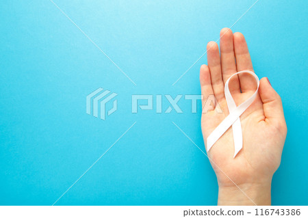 Hand holding white ribbon on blue background. Concept lung cancer awareness. 116743386