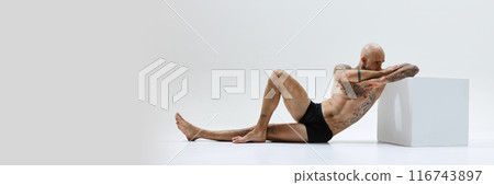 Banner image of handsome bald young man posing shirtless in black underwear, showing muscular athletic body isolated on white studio background Banner image of handsome bald young man posing shirtless in black underwear, showing muscular athletic body isolated on white studio background 116743897
