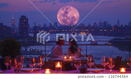Romantic rooftop dinner setting with a couple dining at a candlelit table, overlooking a city skyline, skyscrapers, and a full moon 116744364
