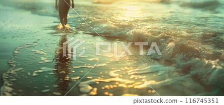 A person walks through the shallow water with sunlight reflecting off the surface. A person walks through the shallow water with sunlight reflecting off the surface. 116745351