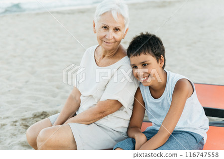 summer vacation at sea. Boy and senior woman at seaside. Grandmother with grandchild are resting on sea, running on beach having fun at summer holiday. Active parents, people activity with children. summer vacation at sea. Boy and senior woman at seaside. Grandmother with grandchild are resting on sea, running on beach having fun at summer holiday. Active parents, people activity with children. 116747558