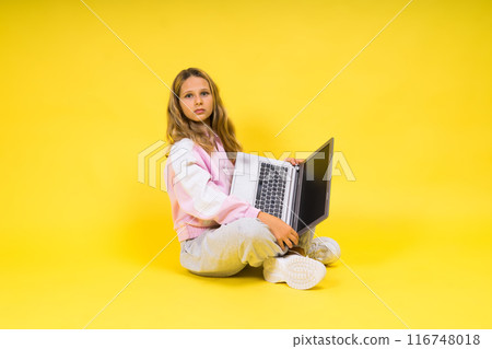 Teenager girl with notebok computer laptop sitting in studio 116748018