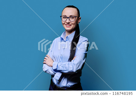 Portrait of smiling business 30s woman with crossed arms on blue background 116748195