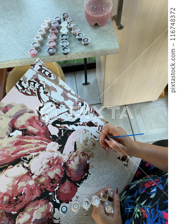 The woman writes a picture by numbers. Paints in numbered jars and a can of water. On open air. Close-up. The woman writes a picture by numbers. Paints in numbered jars and a can of water. On open air. Close-up. 116748372