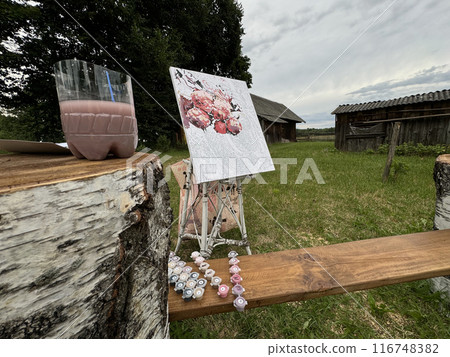 Rication for drawing by numbers on a stand. Paints in numbered jars and a can of water. Lying on a wooden bench. On open air. Rication for drawing by numbers on a stand. Paints in numbered jars and a can of water. Lying on a wooden bench. On open air. 116748382