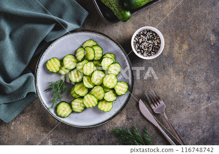 Fresh sliced cucumbers and dill on a plate on the table top view 116748742
