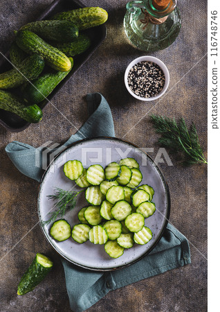 A plate with juicy green slices of cucumber and dill on the table vertical view A plate with juicy green slices of cucumber and dill on the table vertical view 116748746